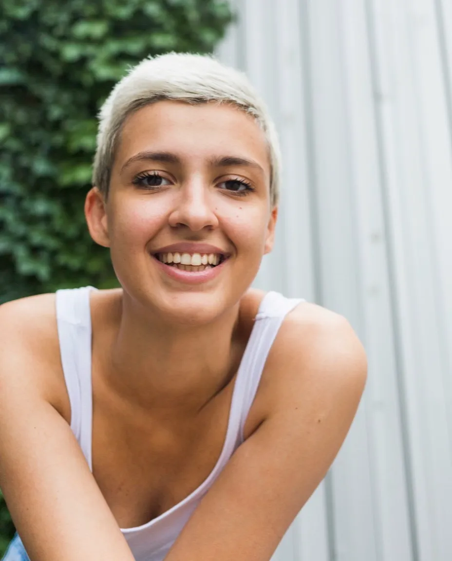 Een lachende vrouw met kort haar, buiten in daglicht